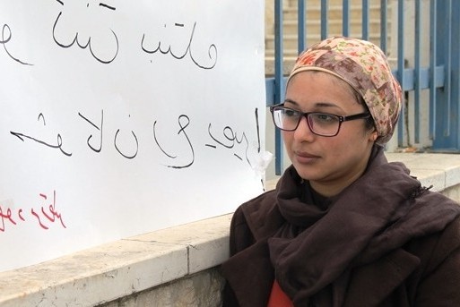 Woman from Palestine with MS, pictured next to a sign saying 'If this was your daughter, what would you do?'