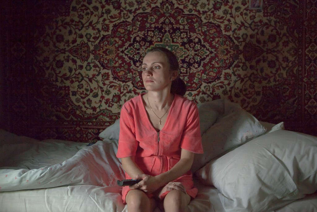 Woman with MS in Belarus watches TV seated on her bed