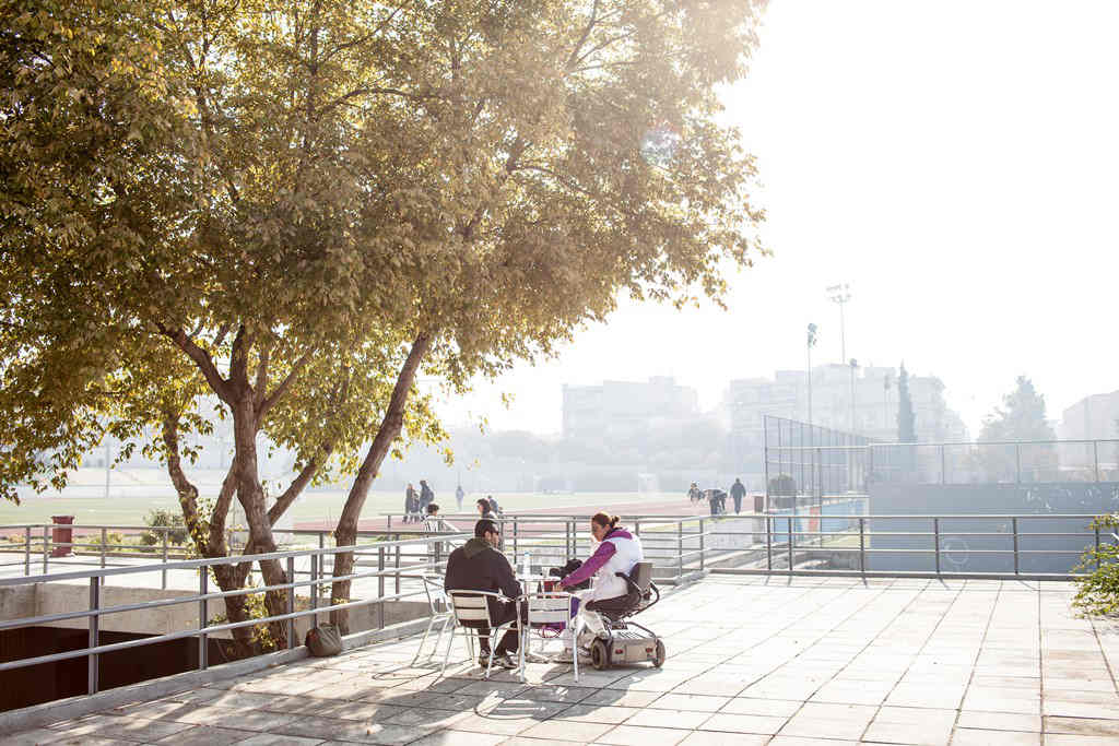 Two people drinking coffee outside in the sunshine