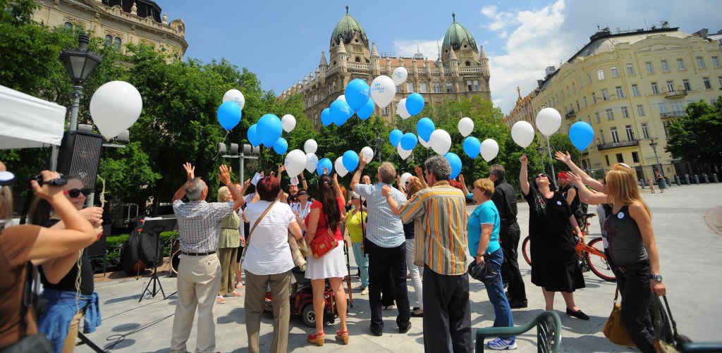 People in a square in Budapest hold balloons to celebrate World MS Day