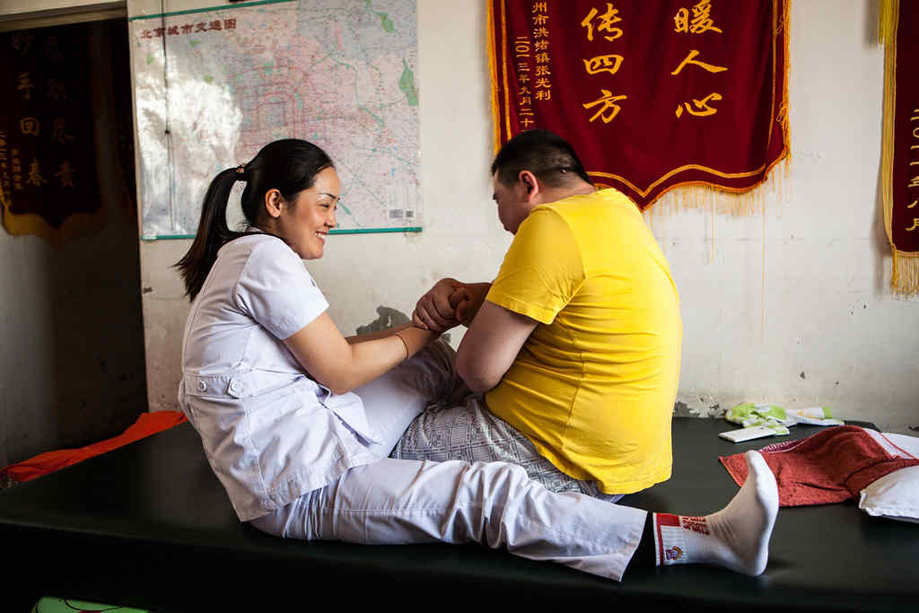 A nurse giving physiotherapy to a man with MS in China