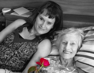 A young woman holds a rose for her grandmother to smell