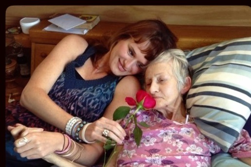 A young woman holds a rose for her grandmother to smell