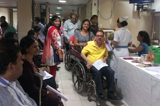 A man in a wheelchair waits in a queue to be seen at a hospital in India, with many others around him