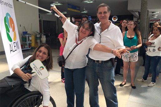 people smiling for the camera in front of an ALCEM banner. One woman stretches her arms mimicing a plane