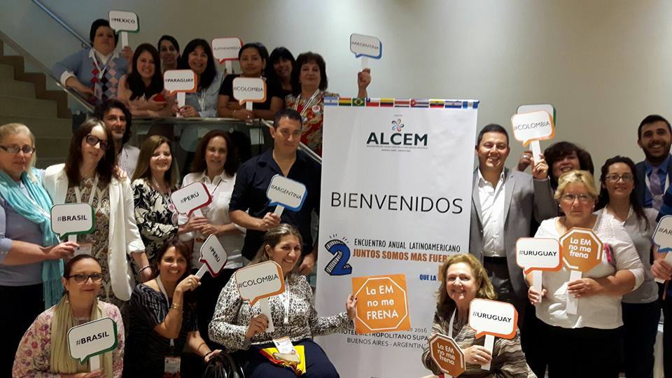 people from across Latin America gather at an event. They are all holding signs with their country name on