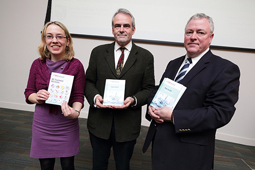 A young woman with blonde hair stands with two men presenting copies of a new MS research publication.