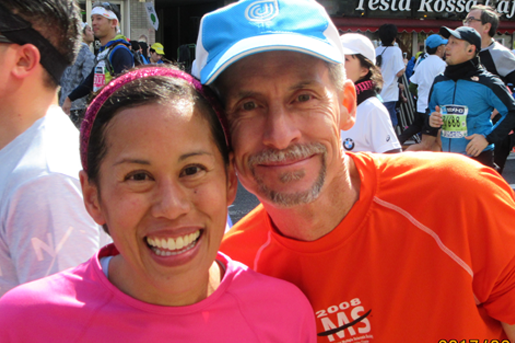 Two runners stand side by side smiling at a marathon
