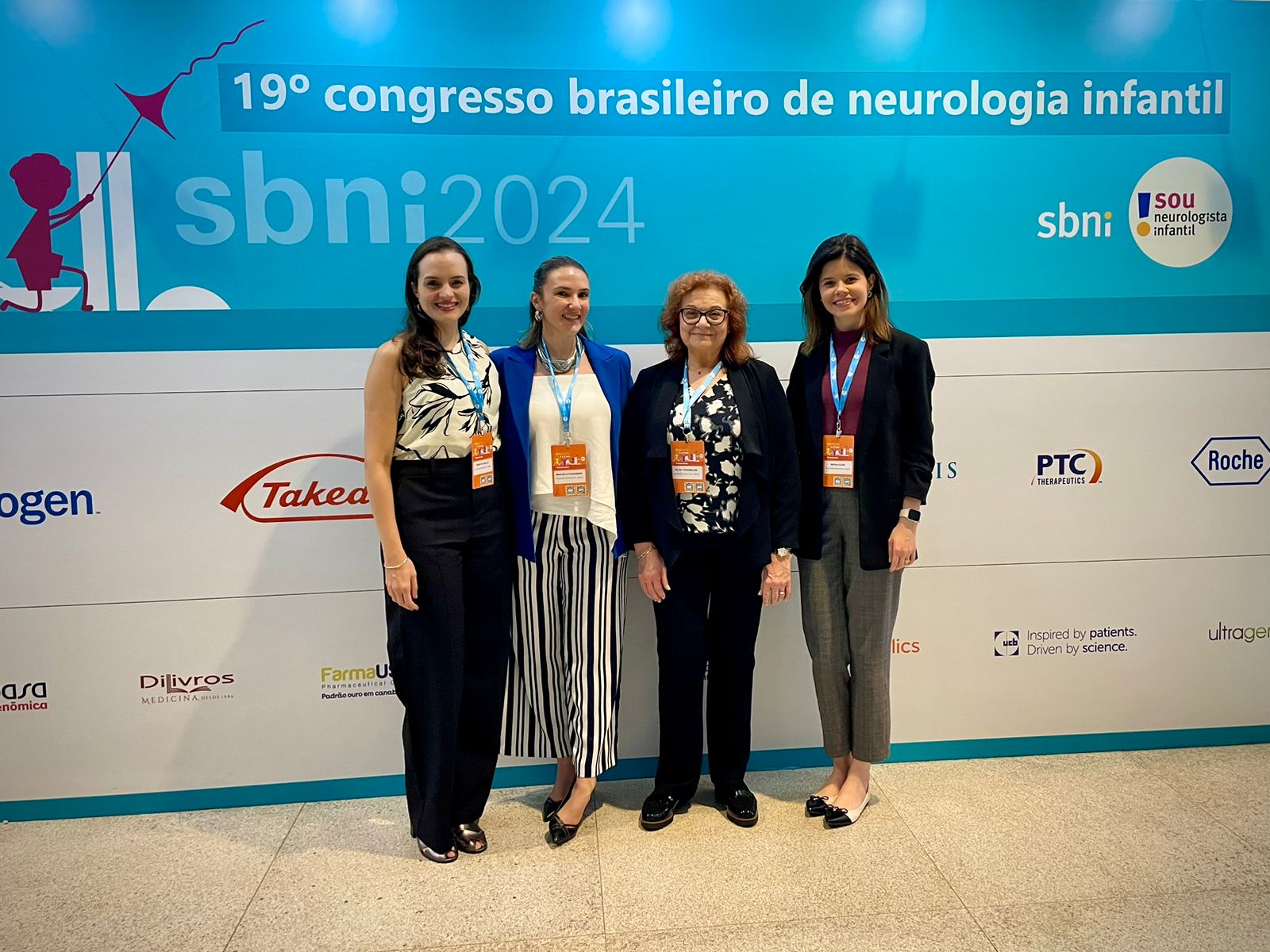 Image of 4 women standing in front of a sign for a brazillian conference